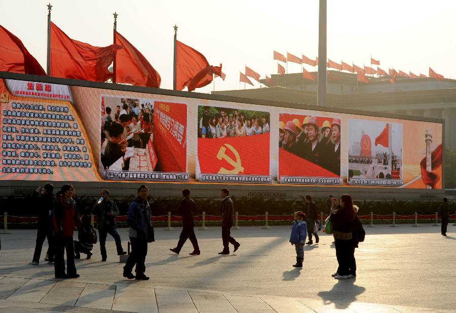 Visitors watch a large screen displaying achievements which China has gained under the leadership of the Communist Party of China (CPC) in the past decade, at the Tian'anmen Square in central Beijing, capital of China, Nov. 8, 2012. The 18th CPC National Congress was opened in Beijing on Thursday. (Xinhua/Luo Xiaoguang)