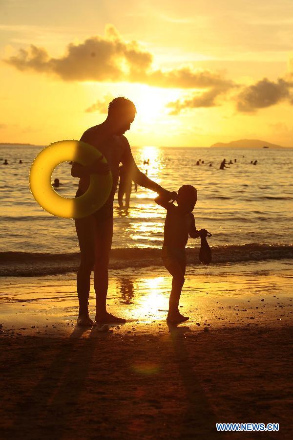 Tourists play on a beach during the sunset in Sanya, south China's island of Hainan Province, Nov. 20, 2012. Though the winter draws near, the tropic seaside city of Sanya remains warm and attracts many tourists. (Xinhua/Chen Wenwu) 