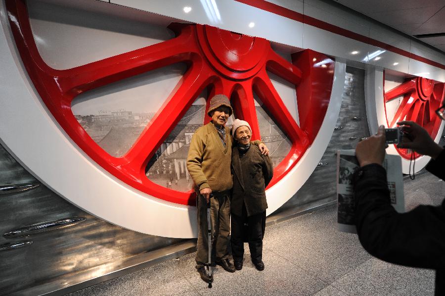 Two senior citizens pose for photo in front of a memorial wall at the Chengzhan Station of Hangzhou Subway Line 1 in Hangzhou, capital of east China's Zhejiang Province, Nov. 24, 2012. Hangzhou Subway Line 1, the first subway in Zhejiang covering a distance of 47.97 kilometers, was put into a trial operation on Saturday after five years of construction. (Xinhua/Ju Huanzong)  