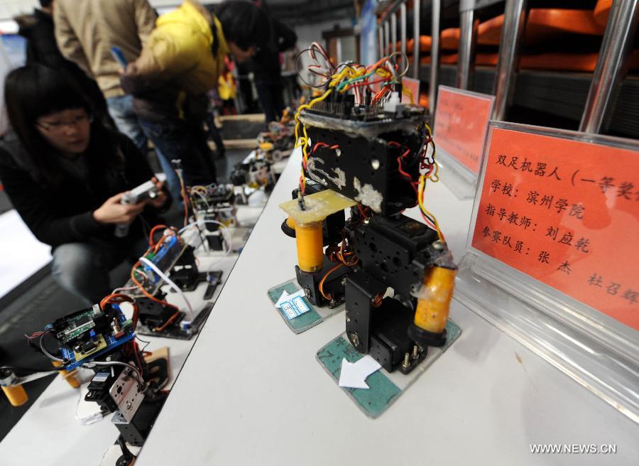 A visitor views robots awarded in a design competition during a robot show held in Qingdao University, Qingdao, east China's Shandong Province, Nov. 25, 2012. The robot show, the first kind of this exhibition in Shandong, showcased the latest achievement of robot-related technology, involving over 100 exhibits from home and abroad. (Xinhua/Guo Xulei) 