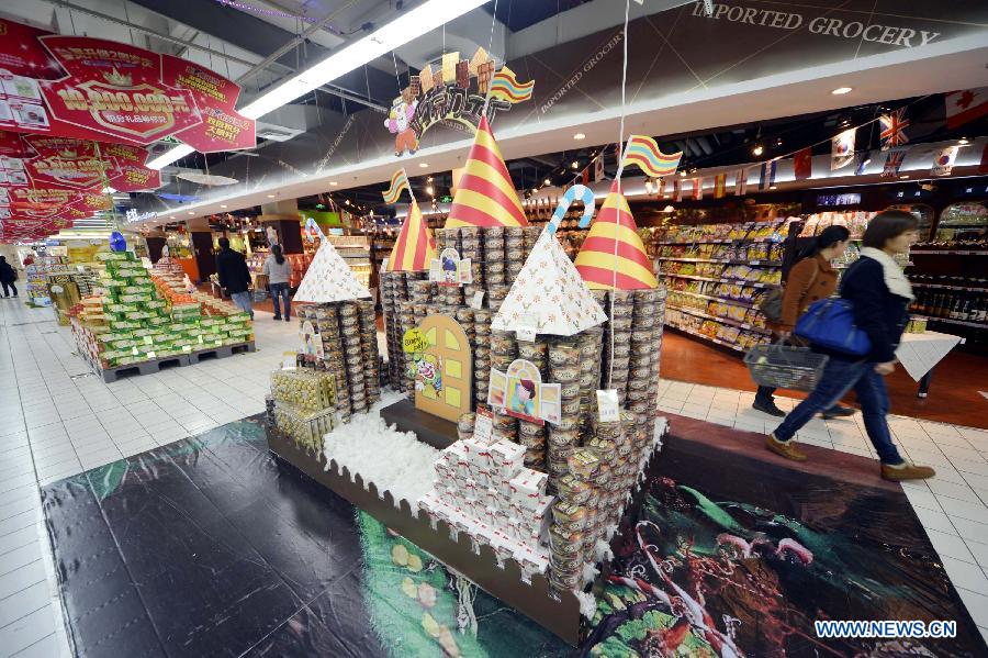 Customers walk past a model of castle laid by commodities at a supermarket in Hangzhou, capital of east China's Zhejiang Province, Nov. 28, 2012. A competion of creative laying of commodities was held here on Wednesday to draw customers' attention. (Xinhua/Shi Jianxue)