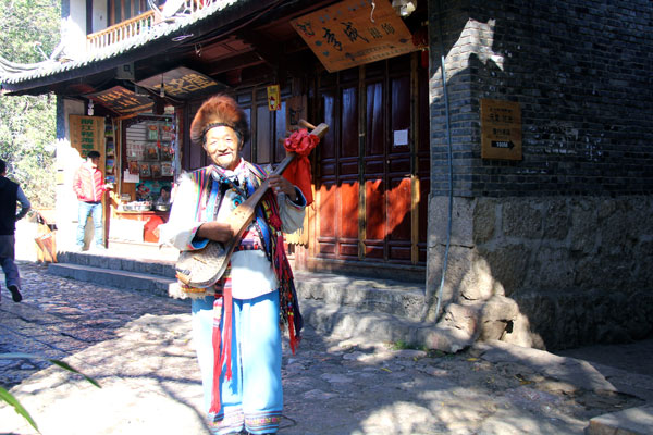 An old man dressed in a heavily decorated ethnic costume poses for photo on the main business street of Shuhe Ancient Town. (CRI Photo)