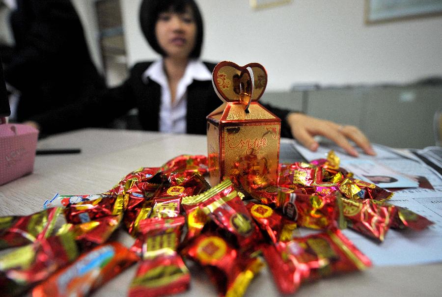 A staff member works for the couples at the marriage registration office in Haikou, capital of south China's Hainan Province, Jan. 4, 2013. Quite a number of couples flocked to tie the knot on Jan. 4, 2013, or 2013/1/4, which sounds like "Love you forever" in Chinese. (Xinhua/Guo Cheng)