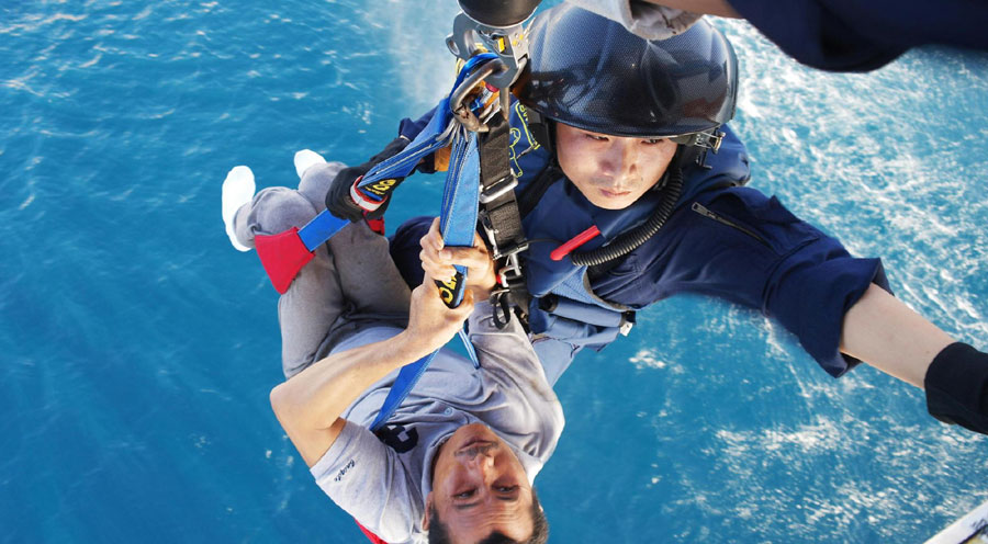 A Ministry of Transport rescuer lifts a sick fisherman up to a helicopter in the South China Sea on Nov 18, 2012. (Photo/Xinhua)