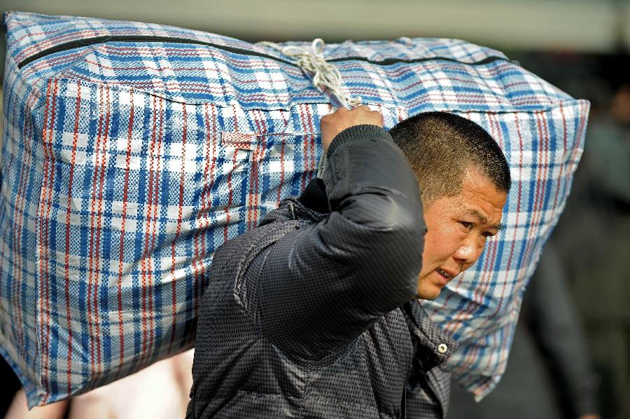 A man carries his bag on the square of the train station in Chengdu, capital of southwest China's Sichuan Province, Jan. 24, 2013. As the spring festival approaches, more than more people started their journey home. (Xinhua/Xue Yubin) 