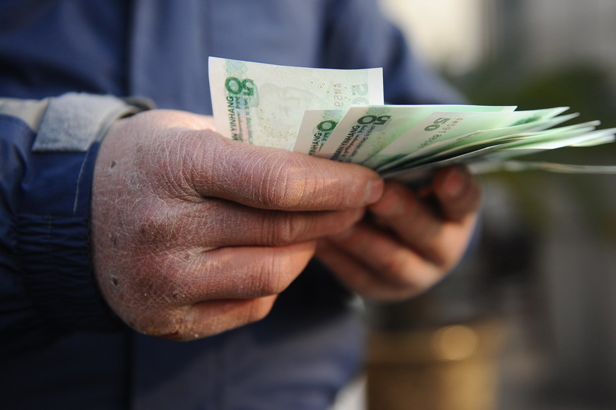 A migrant worker counts his arrear wages on Jan. 24. 71 migrant workers received their arrear wages of 292,000 yuan in total. (Photo/Xinhua)