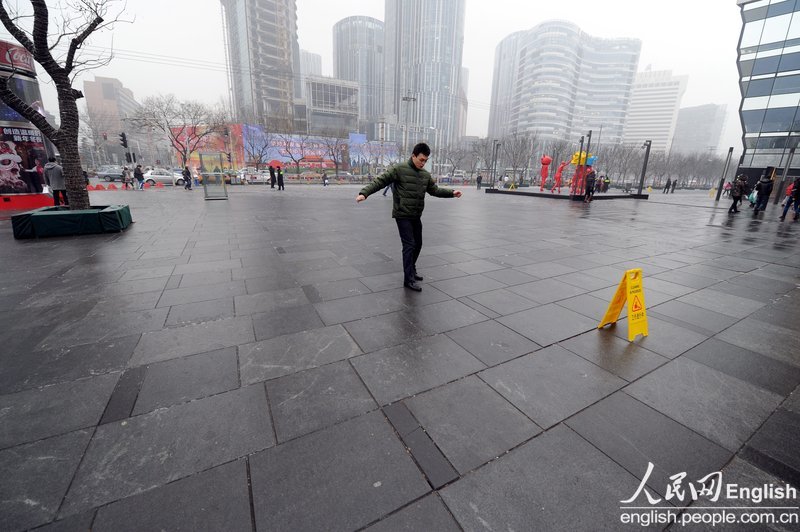 Rain and light snow falls in Beijing slightly disperse the lingering smog that suffocated the city for a few days. A fresh cold front hit the central and eastern China on Thursday and was expected to ease the smog that suffocated these areas in the past few days. Because of the freezing temperature, the rainwater turned to thin ice on the road, leading to many slips and traffic accidents in Beijing on Thursday. (Photo/CFP)