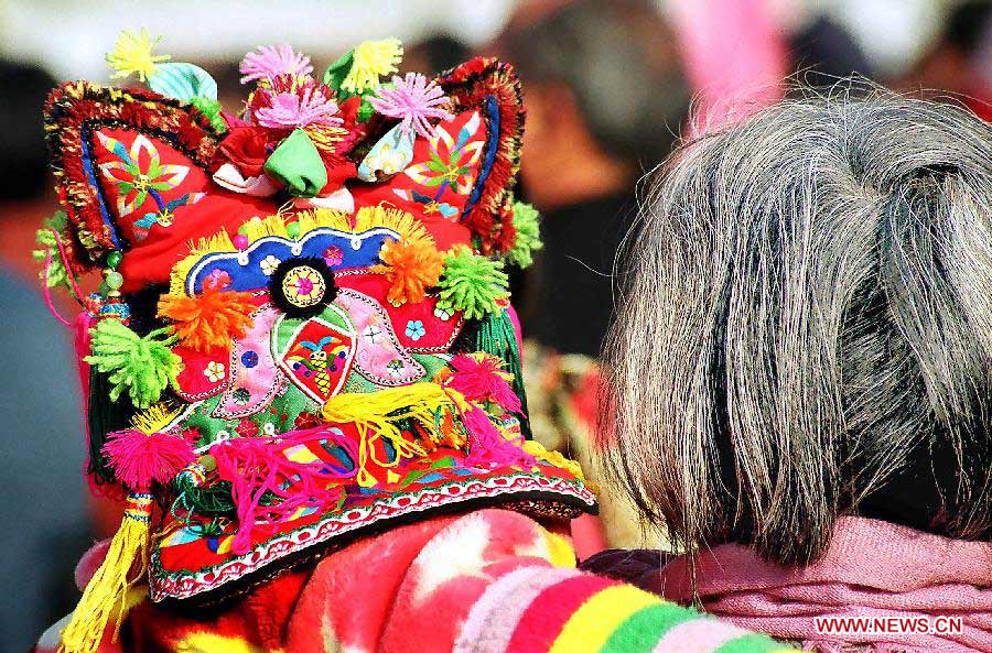 A grandma holds her grandchild who wears a traditional tiger hat as they head for a New Year fair in Tuocheng County, central China's Henan Province, Jan. 20, 2004. People living in the central China's region usually follow a tradition to wear new clothes and children are dressed with tiger hats or shoes to ward off eveil spirits during the Spring Festival or Chinese Lunar New Year. (Xinhua/Wang Song)