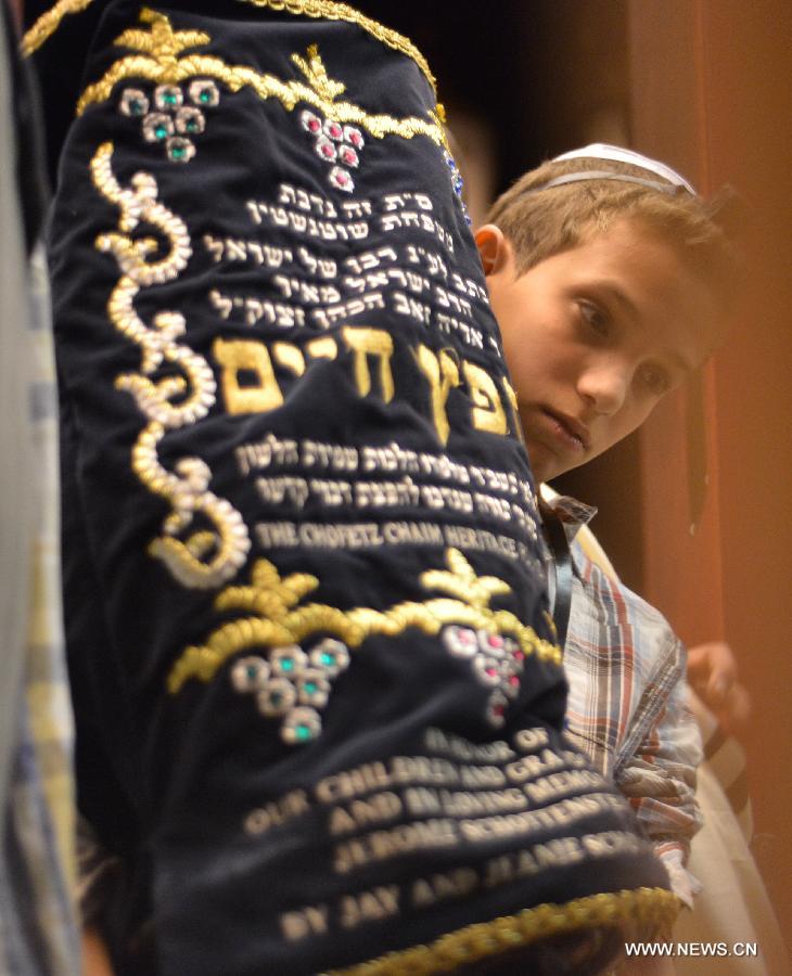 A 13-year-old Jewish boy (C) is surrounded by his family members during his Bar Mitzvah ceremony to be recognized by Jewish tradition as having the same rights as a fully grown man, at the Western Wall Plaza in Jerusalem's Old City on Feb. 4, 2013. (Xinhua/Yin Dongxun)