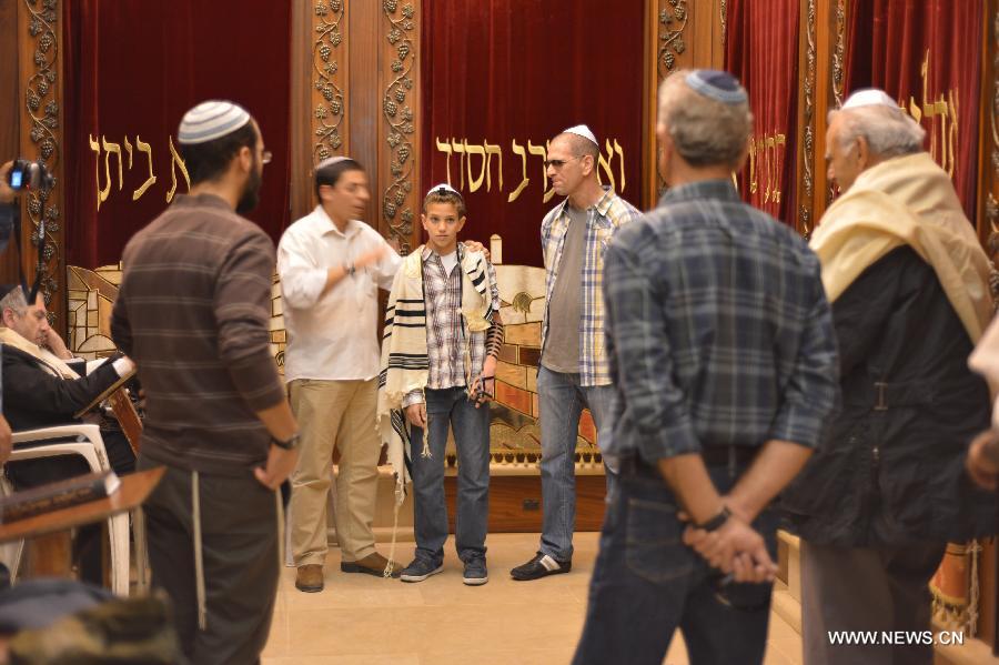 A 13-year-old Jewish boy (C) is surrounded by his family members during his Bar Mitzvah ceremony to be recognized by Jewish tradition as having the same rights as a fully grown man, at the Western Wall Plaza in Jerusalem's Old City on Feb. 4, 2013. (Xinhua/Yin Dongxun)