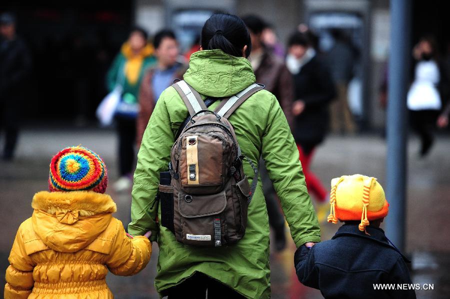 A woman takes two children by the hand as the three of them head for the Guiyang Railway Station in Guiyang, capital of southwest China's Guizhou Province, Feb. 17, 2013. When the Spring Festival holiday comes to an end, migrant workers start to leave their hometowns in Guizhou for job opportunities in China's more affluent coastal provinces. Many have to take their children with them. (Xinhua/Liu Xu)