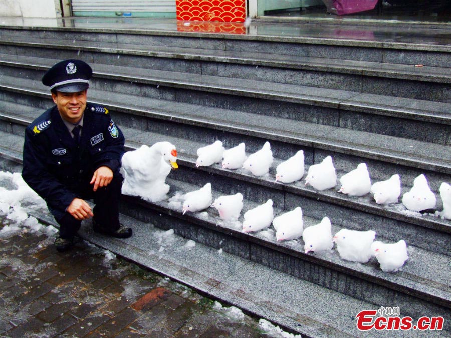 Mr. Du takes photo with the snow sculptures he made in Hangzhou, the capital city of East China's Zhejiang Province, February 19, 2013. The sculptures, including one goose and 16 chicks, impressed many passers-by on Tuesday. The 49-year-old security guard has become addicted to snow carving since three years ago. (CNS/Wu Jiawei)