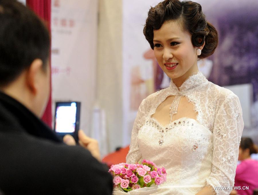 A visitor takes photos of a model wearing wedding dress during a wedding expo in Suzhou City, east China's Jiangsu Province, March 1, 2013. (Xinhua/Hang Xingwei)