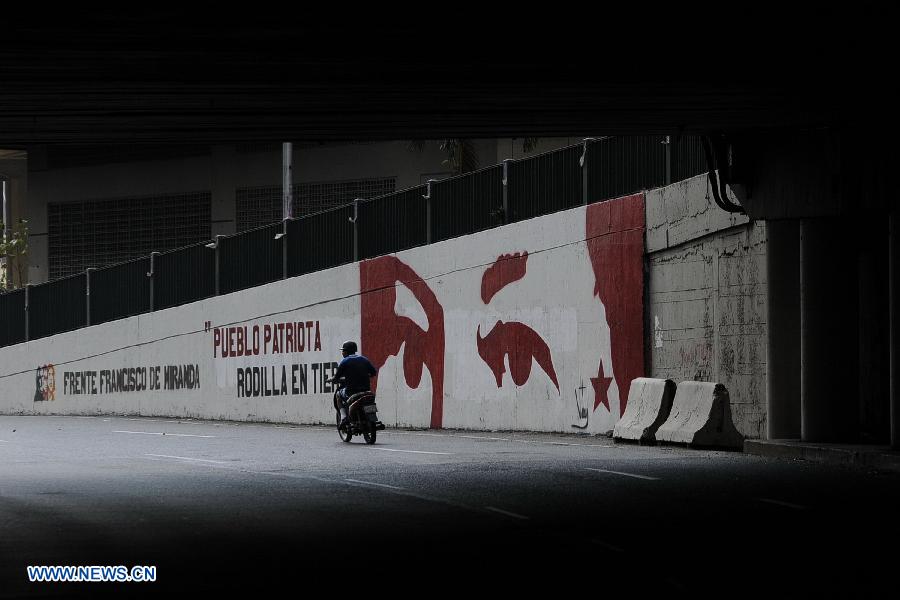 A resident rides past a wall with a painting of Venezuelan President Hugo Chavez on a street in Caracas, capital of Venezuela, on Mar. 2, 2013. Venezuela's ailing President Hugo Chavez is undergoing chemotherapy in the capital's military hospital, Vice President Nicolas Maduro said Friday, calling for respect for Chavez and his family. (Xinhua/Mauricio Valenzuela)