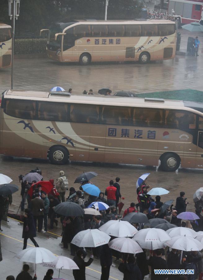 Journalists and staff members wait for the arrvial of members of the 12th National Committee of the Chinese People's Political Consultative Conference (CPPCC) in rain in Beijing, capital of China, March 12, 2013. The closing meeting of the first session of the 12th CPPCC National Committee is to be held in Beijing on Tuesday. (Xinhua/Wang Jianmin)  