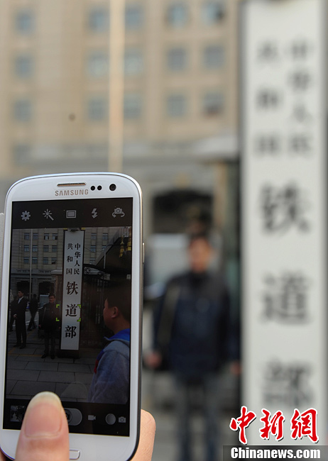 Nostalgic residents line up outside the headquarters of the Ministry of Railway to take photos with its sign yesterday afternoon. On the day, the first session of the 12th NPC endorsed the government restructuring plan, according to which the Ministry of Railway would be dissolved.（Photo/Chinanews.com）