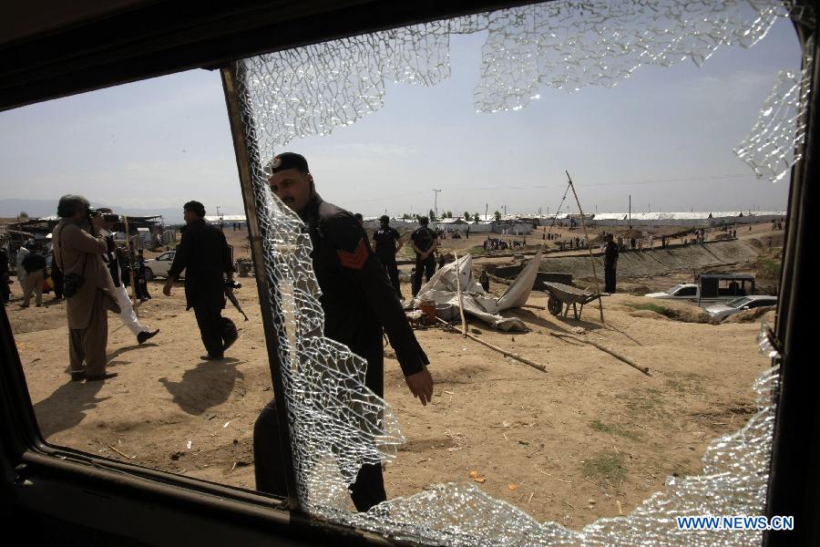 Security officials examine a damaged vehicle at the site of a bomb attack at the Jalozai refugee camp in northwest Pakistan's Nowshera on March 21, 2013. At least 12 people were killed and 35 others injured when a bomb hit a refugee camp in Nowshera on Thursday morning, local officials said. (Xinhua Photo/Umar Qayyum)