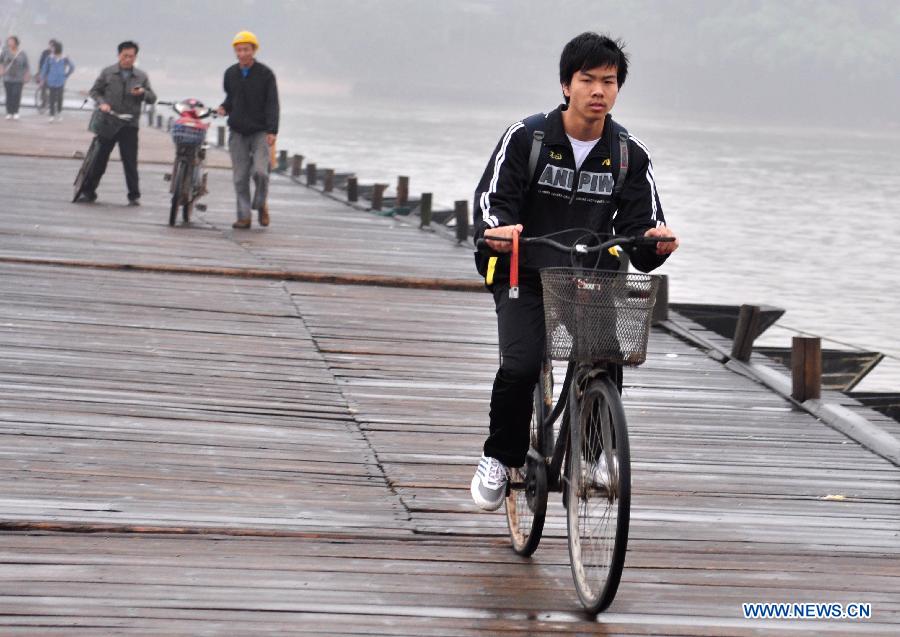 A man rides on an ancient floating bridge across the Gongjiang River in Ganzhou, east China's Jiangxi Province, April 1, 2013. The wooden bridge, running 400 meters, is supported by some 100 floating boats anchored in a row. The bridge could date back to the time between 1163 and 1173 during the Song Dynasty, and has become a scene spot of the city. (Xinhua) 