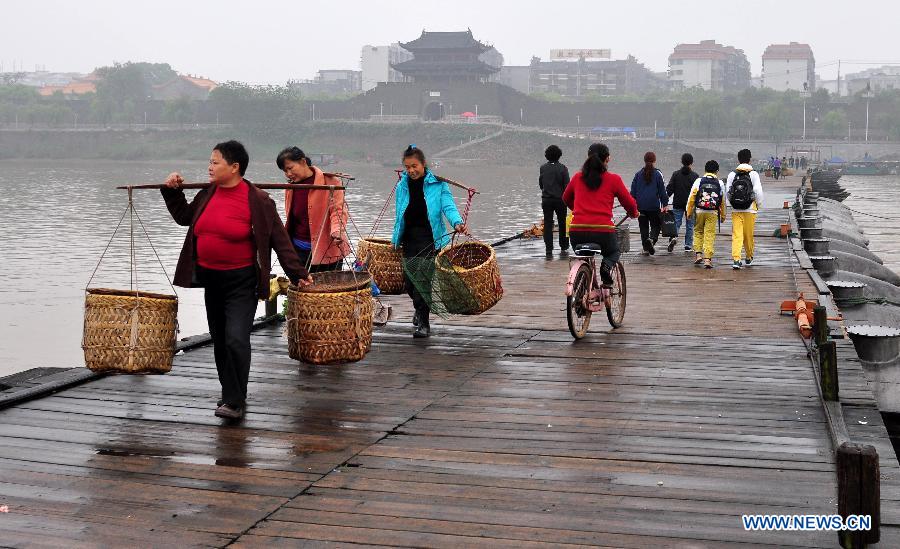 People walk on an ancient floating bridge across the Gongjiang River in Ganzhou, east China's Jiangxi Province, April 1, 2013. The wooden bridge, running 400 meters, is supported by some 100 floating boats anchored in a row. The bridge could date back to the time between 1163 and 1173 during the Song Dynasty, and has become a scene spot of the city. (Xinhua) 