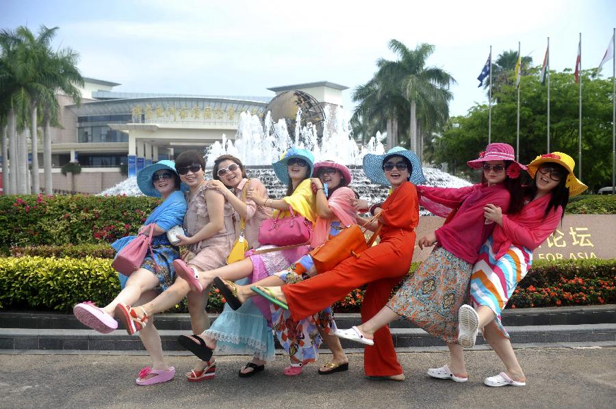 Visitors pose for photo in front of the convention center for Boao Forum for Asia (BFA) Annual Conference 2013 in Boao, south China's Hainan Province, April 2, 2013. The BFA 2013 conference will be held from April 6 to 8 in Boao. (Xinhua/Meng Zhongde)