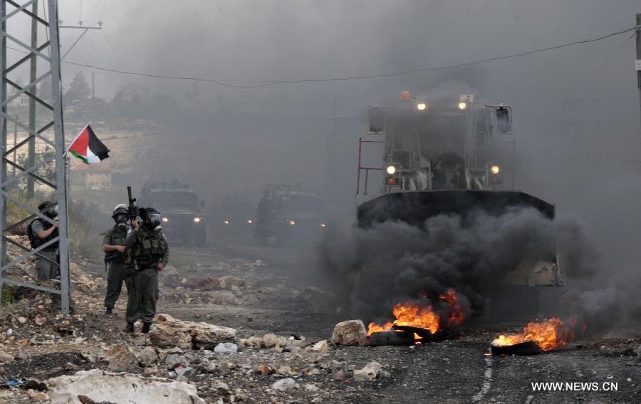 An Israeli bulldozer tries to remove burning tires from the road during a Palestinian protest against the expanding of Jewish settlements in Kufr Qadoom village near the West Bank city of Nablus on Apr. 5, 2013 (Xinhua/Nidal Eshtayeh)