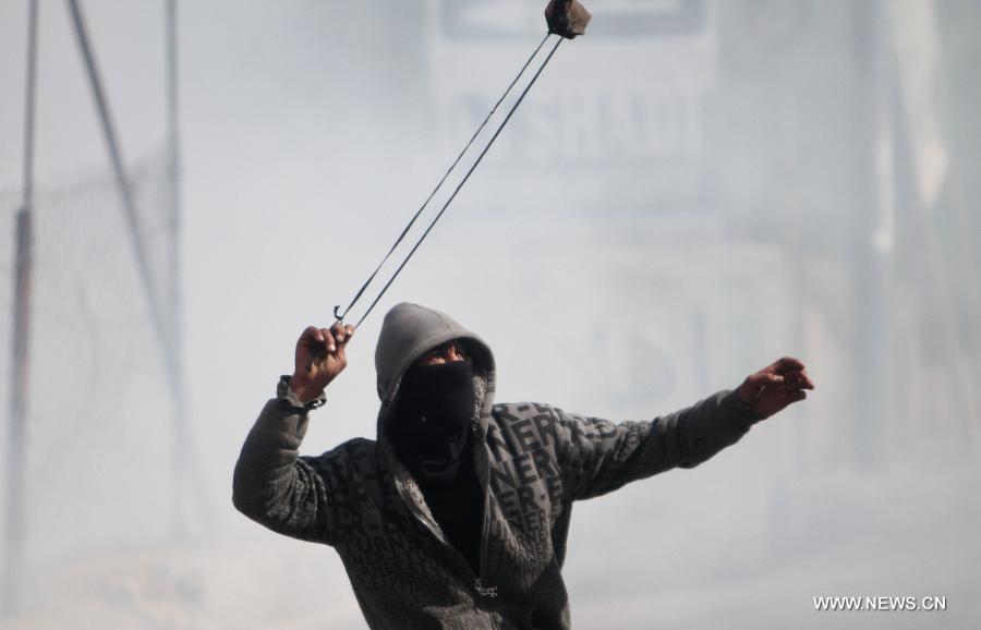 A Palestinian youth hurls stones toward Israeli soldiers during clashes in the West Bank village of al-Khader near city of Bethlehem, April 5, 2013. (Xinhua/Luay Sababa)