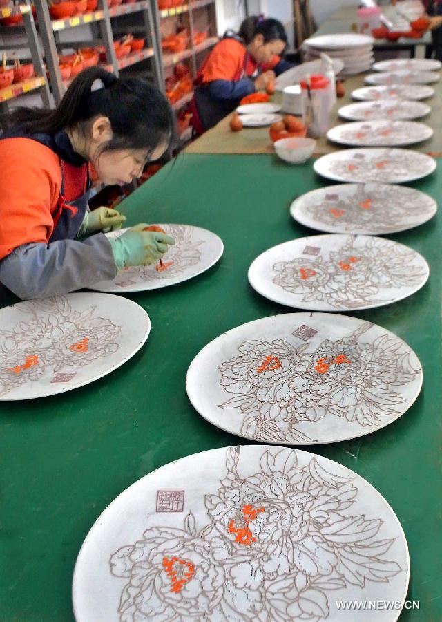 Craftswomen glaze porcelain paintings of peony at a ceramic factory in Luoyang, central China's Henan Province, Oct. 29, 2012. Known as the "city of peony", Luoyang has created an industry chain on peony in recent years. Various crafts and products of peony have been developed to serve the local economy. (Xinhua/Wang Song)