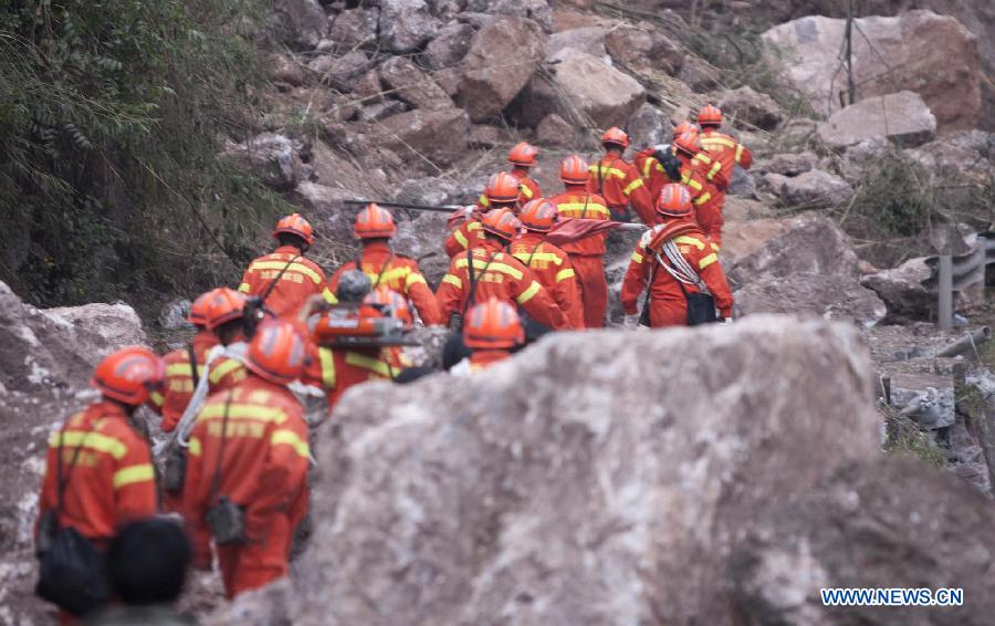 Rescuers try to pass through a road blocked by fallen rocks due to the landslide in Baosheng Township, Lushan County, southwest China's Sichuan Province, April 21, 2013. Baosheng Township is another seriously affected area in Lushan. Search and rescue work continued here Sunday, and the work for restoring roads and communications are conducted in the pipelines. (Xinhua/Fei Maohua)