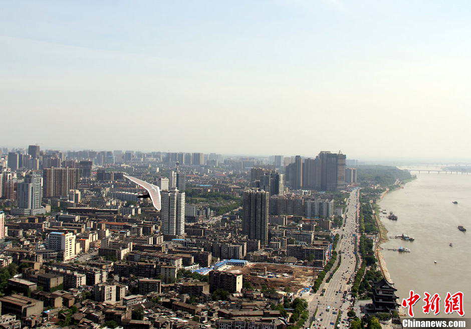 Yang Longfei, an amateur hang glider from Hebei province, soars across the Xiang River in Changsha, Central China's Hunan province, May 1, 2013. After successfully covering a distance of 1,500 meters, Yang became the first person in the world to complete an unpowered flight within a city. (Photo/Chinanews.com)