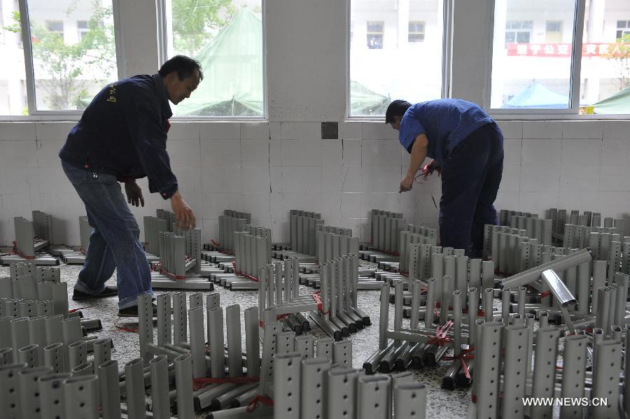 Staff members check newly-arrived desk parts by donators at a school served as an evacuation settlement for displaced people in the quake-hit Baoxing County, southwest China's Sichuan Province, May 2, 2013. Some 4,000 displaced people live the settlement, the largest in the county, after a strong earthquake hit Baoxing last month. At present, basic living needs of those people could be guaranteed in terms of food, drink, healthcare service and power supply. (Xinhua/Lu Peng)