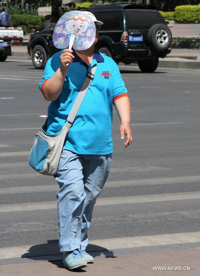 A citizen walks under the hot sun in Baoding City, north China's Hebei Province, May 11, 2013. A hot wave hit Hebei these days, with the highest temperature in parts of the province reaching 37 degrees Celsius. (Xinhua/Zhu Xudong) 