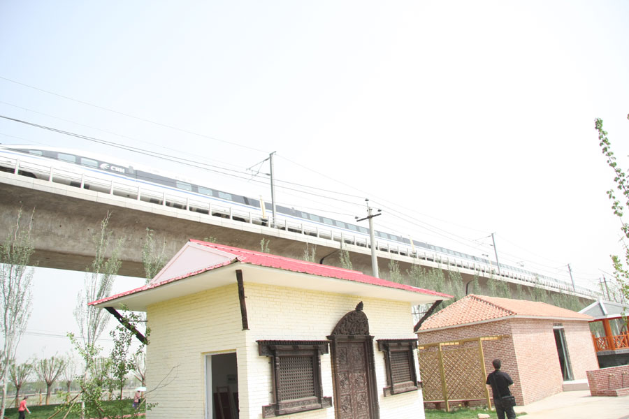 A high-speed train on an overpass raging through the Ninth China (Beijing) International Garden Expo in western Beijing. The expo covers an area of 513 hectares, including 267-hecare public exhibition area and 246-hectare Garden Expo Lake. The event will officially kick off on May 18, 2013 and last for six months. (CRIENGLISH.com/Luo Dan)