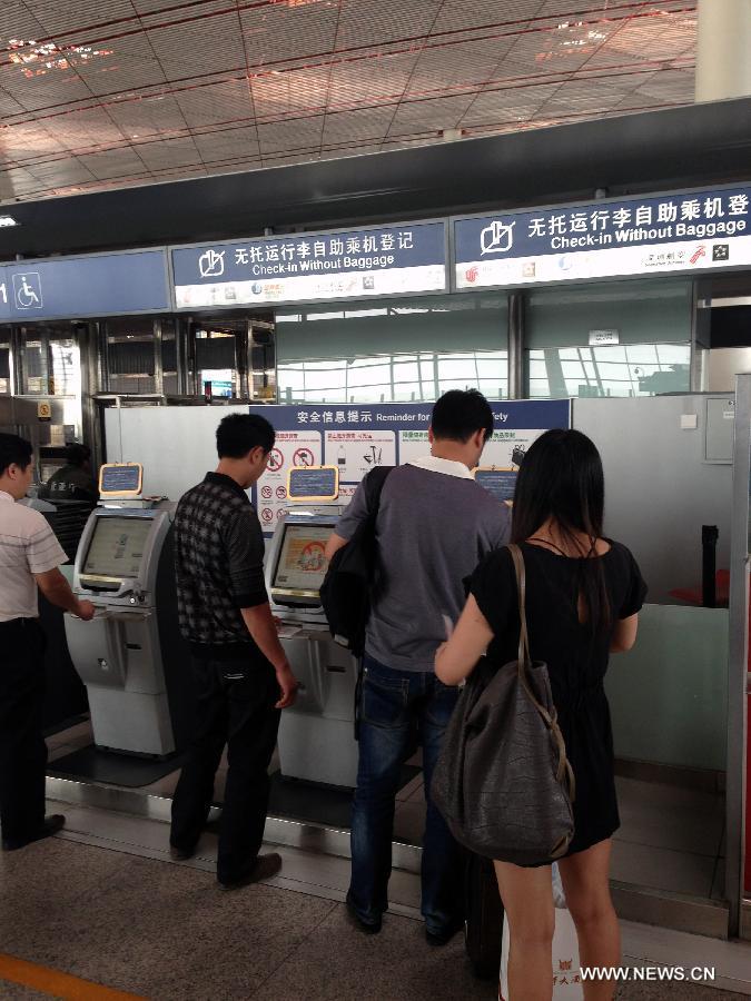 Passengers check in at self-service area at Capital International Airport in Beijing, capital of China, May 15, 2013. Three Chinese airlines were targeted by false bomb threats Wednesday morning. Five flights operated by China Eastern Airlines, Juneyao Airlines and Shenzhen Airlines were affected. (Xinhua)