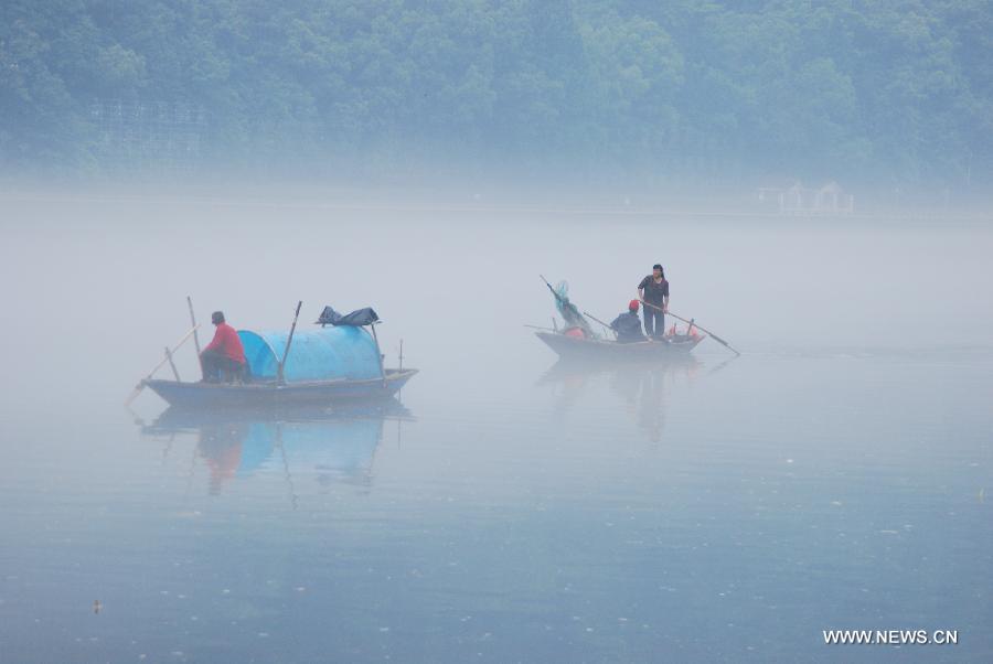 Fisherman steer boats through fogs on the Xin'an River in Jiande, east China's Zhejiang Province, May 15, 2013. (Xinhua/Ning Wenwu)