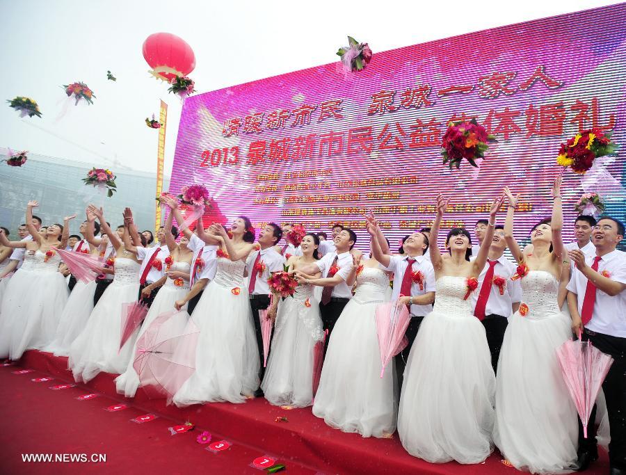 Newly-wed couples are seen at a group wedding ceremony for migrant workers in Jinan, capital of east China's Shandong Province, May 26, 2013. A group wedding was held for migrant workers here on Sunday, with 31 pairs of newly-wed couples participating. (Xinhua/Cui Jian)