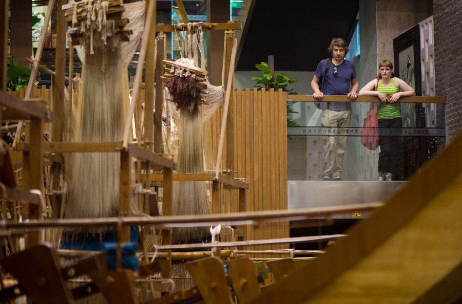 Foreign tourists watch a traditional loom in Chengdu, capital of Sichuan, May 27, 2013. Imparted from generation to generation for over 2,000 years, Shu brocade weaving techniques have been put on China's Intangible Cultural Heritage List in 2006. (Xinhua/Li Qiaoqiao) 