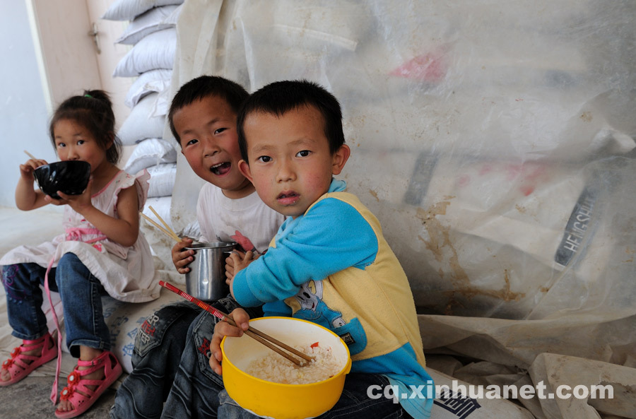 Junior students have their meal sitting on the bags of fertilizer at lunch time since there’s no cafeteria at school. (Photo by Huang Junhui/ cq.xinhuanet.com)