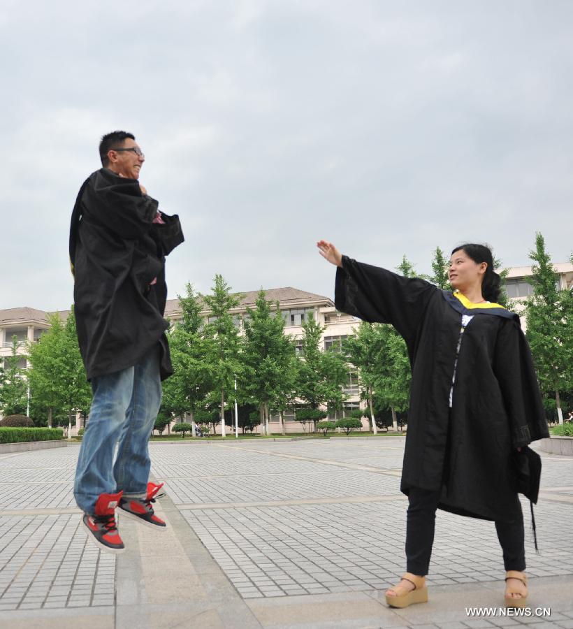 Graduates wearing academic dresses pose for photos at Zhejiang Agriculture and Farming University in Hangzhou, capital of east China's Zhejiang Province, May 26, 2013. (Xinhua/Hu Jianhuan) 