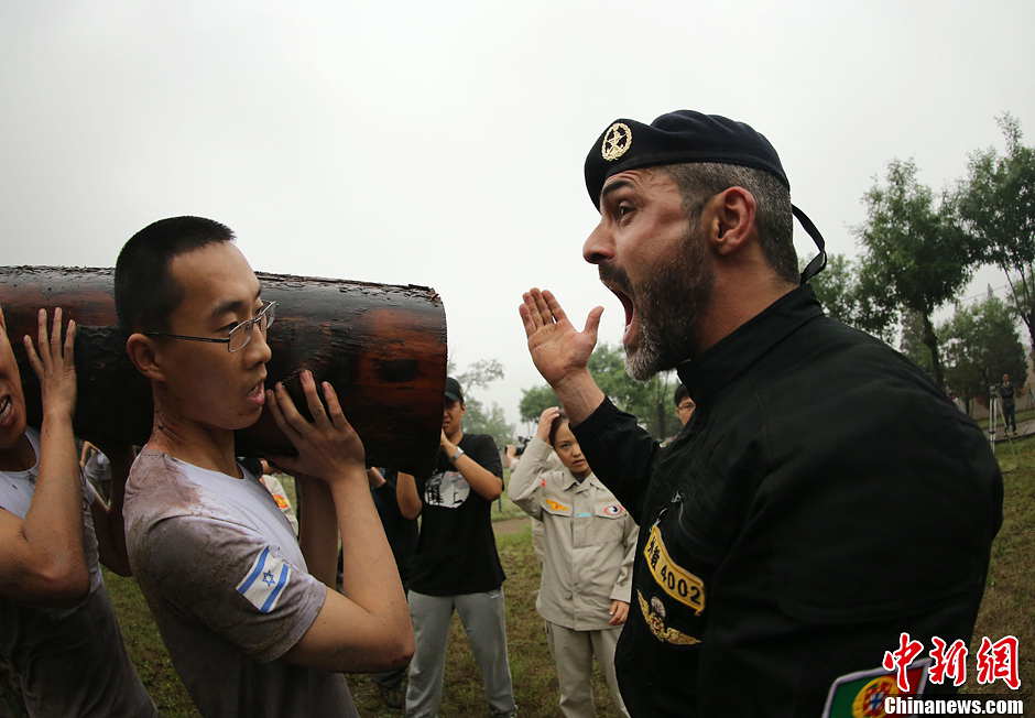 Trainees lift a log during a VIP security training course at the Genghis Security Academy in Beijing, June 6, 2013. More than 70 trainees, including six women and three foreigners will receive high-intensity training for VIP security at a bodyguard camp in Beijing. They will train over 20 hours per day for one week. One third of the participants will be phased out at the end of the "Hell Week".  (Photo/ Chinanews.com)