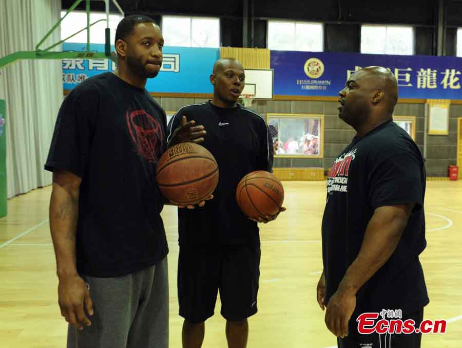 Tracy McGrady (L) autographs a basketball on a basketball court at the Jin Qiang national basketball training base in Chengdu, Southwest China's Sichuan Province, June 24, 2013. NBA stars visited Chengdu and played a game against China's August 1 Men's Basketball Team on Monday. (CNS/Liu Zhongjun)