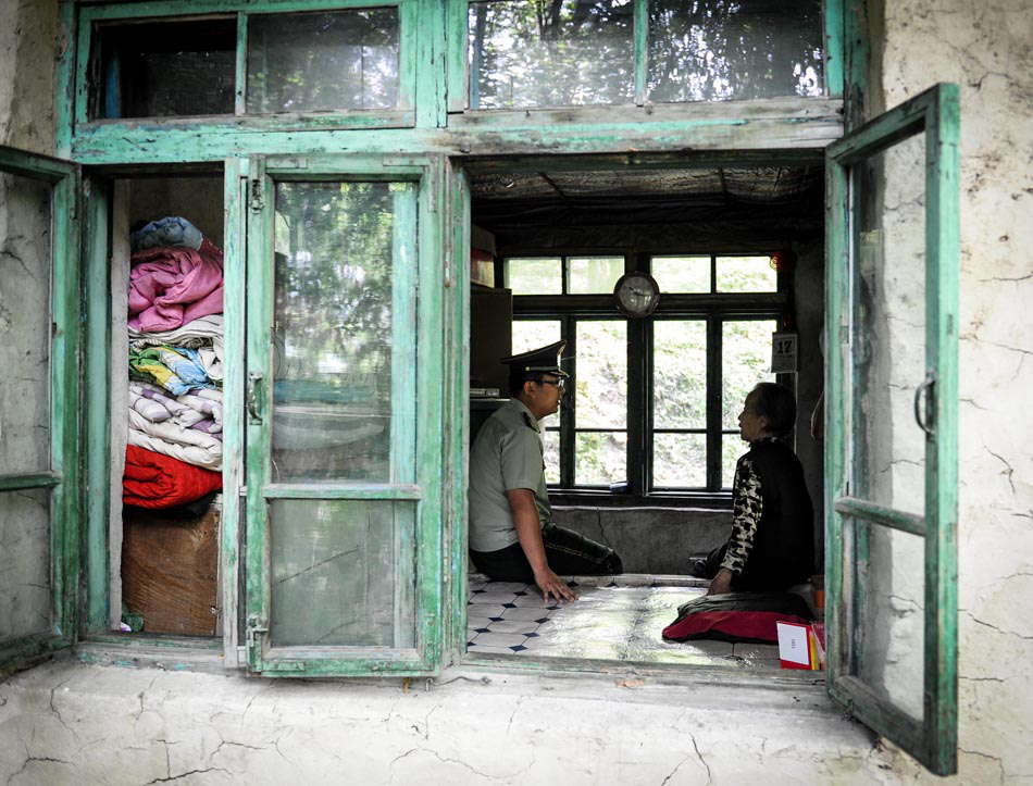 Wang Dawei (L) talks with Zang Yuzhen, 82, who cultivates Chinese ginseng and temporarily lives in mountains in northeast China's JInlin province on June 18, 2013. Wang, the border police officer and his team are honored as guardian god in the village. (Photo by Xu Chang/ XInhua)