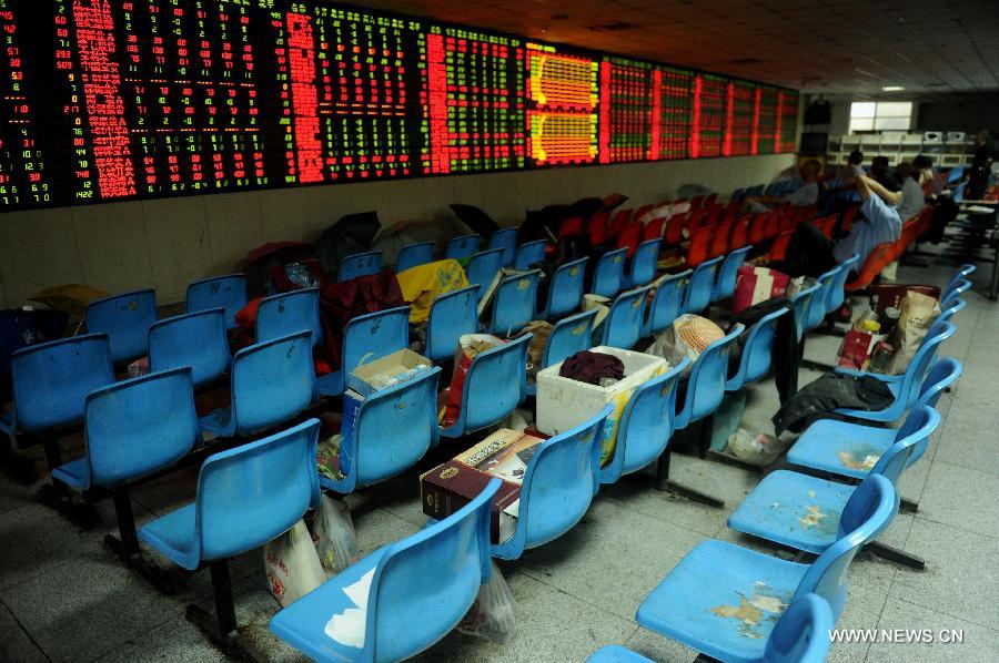 Investors look at the stock information at a trading hall of a securities firm in Hefei, capital of east China's Anhui Province, June 25, 2013. Chinese shares extended losses on Tuesday following Monday's drastic slump as the benchmark Shanghai Composite Index lost 0.19 percent, or 3.73 points, to end at 1,959.51, the lowest point in nearly seven months. The Shenzhen Component Index shrank 1.23 percent, or 93.43 points, to 7,495.10. (Xinhua/Ma Qibing)