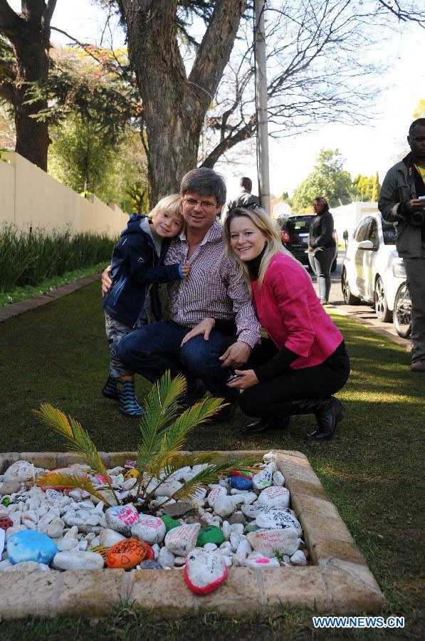 Members of a local family pose for a group photo beside colorful stones with best wishes for South Africa's anti-apartheid icon Nelson Mandela outside his residence in Johannesburg, South Africa, June 27, 2013. South African President Jacob Zuma has canceled his scheduled visit to Mozambique after visiting former president Nelson Mandela in hospital, the Presidency said Wednesday night. (Xinhua/Guo Xinghua)