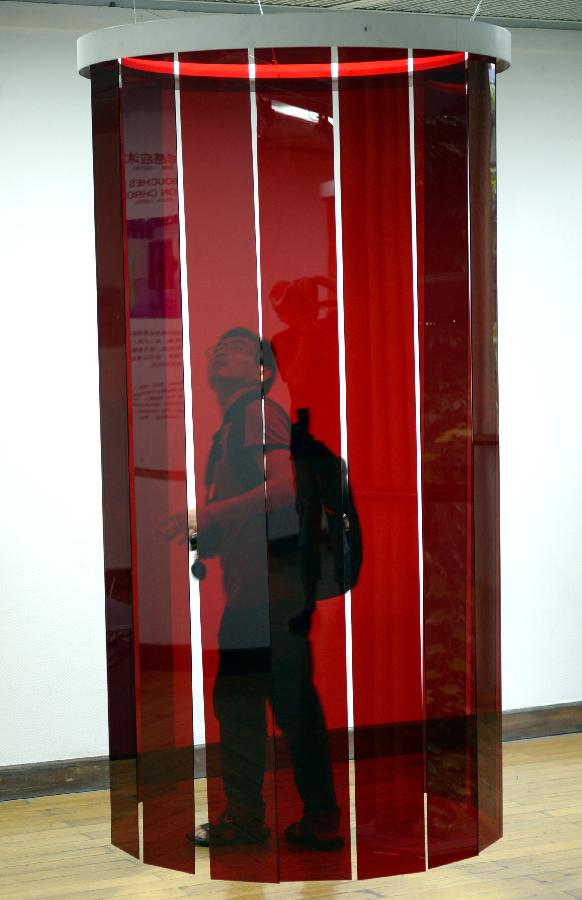 A visitor looks at an artwork during the exhibition of the Venezuelan artist Carlos Cruz-Diez "Circumstance and Ambiguity of Color" in Hangzhou, capital of east China's Zhejiang Province, June 27, 2013. The exhibition will last till July 23. (Xinhua/Shi Jianxue)  