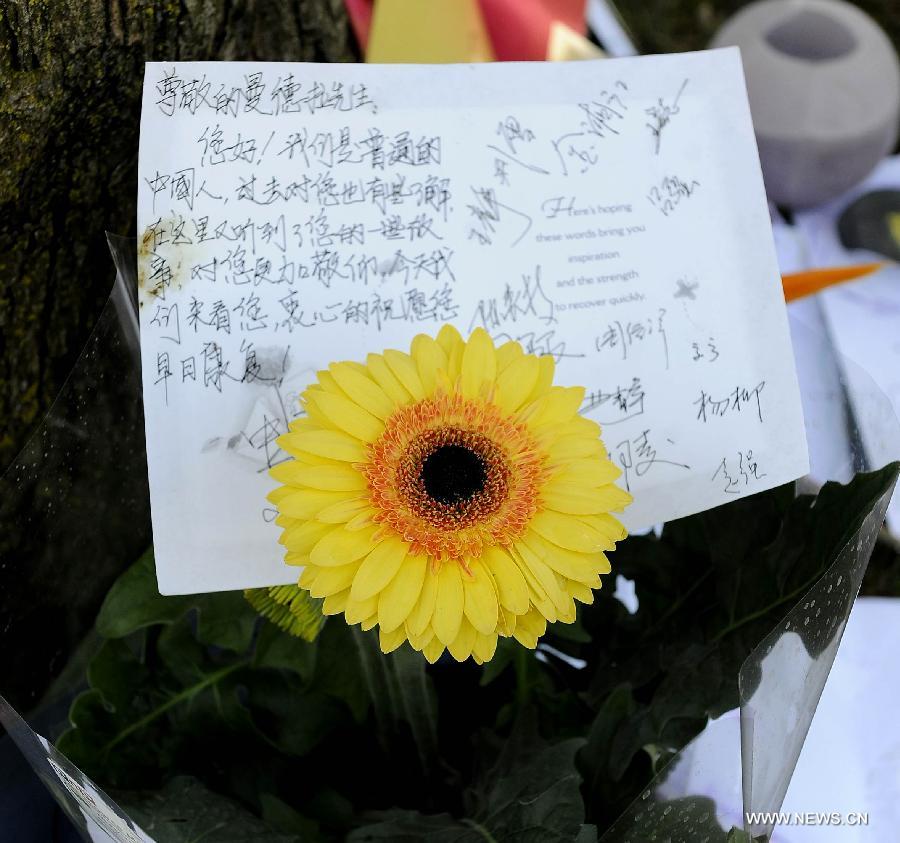 A card with praying words and flowers are presented to South African former president Nelson Mandela outside Mandela's house in Johannesburg, South Africa, on July 3, 2013. Mandela is breathing by medical life support measures under the condition described as "perilous" by family members in a court paper-work released on Wednesday. (Xinhua/Li Qihua)