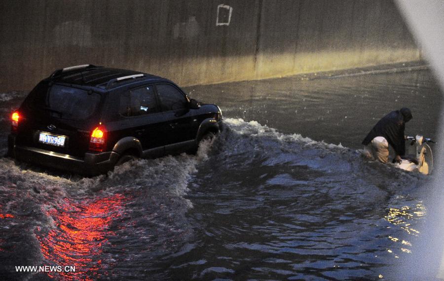 A vehicle moves on a waterlogged road in Tianjin, north China, July 4, 2013. A rainstorm hit Tianjin on Thursday, causing waterlogging in part of the city. (Xinhua/Yue Yuewei) 