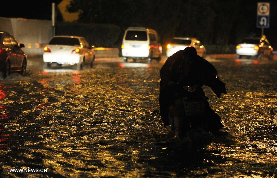 A citizen walks his or her electric bicycle on a waterlogged road in Tianjin, north China, July 4, 2013. A rainstorm hit Tianjin on Thursday, causing waterlogging in part of the city. (Xinhua/Yue Yuewei) 