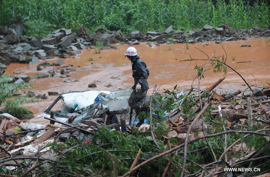 A fire fighter walks on muds while searching for survivors at the Sanxi Village, in Dujiangyan City, southwest China's Sichuan Province, July 11, 2013. As of 2:10 p.m. Thursday, rescuers had found 18 bodies from the landslide that happened on Wednesday morning in the village of Sanxi. (Xinhua/Xue Yubin)