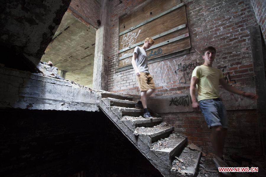 Two Belgian tourists explore the Packard Plant, an abandoned auto factory, in Detroit, midwest city of the United States, July 19, 2013. U.S. city Detroit filed for bankruptcy Thursday, making it the largest-ever municipal bankruptcy in U.S. history, local media reported. (Xinhua/Marcus DiPaola)