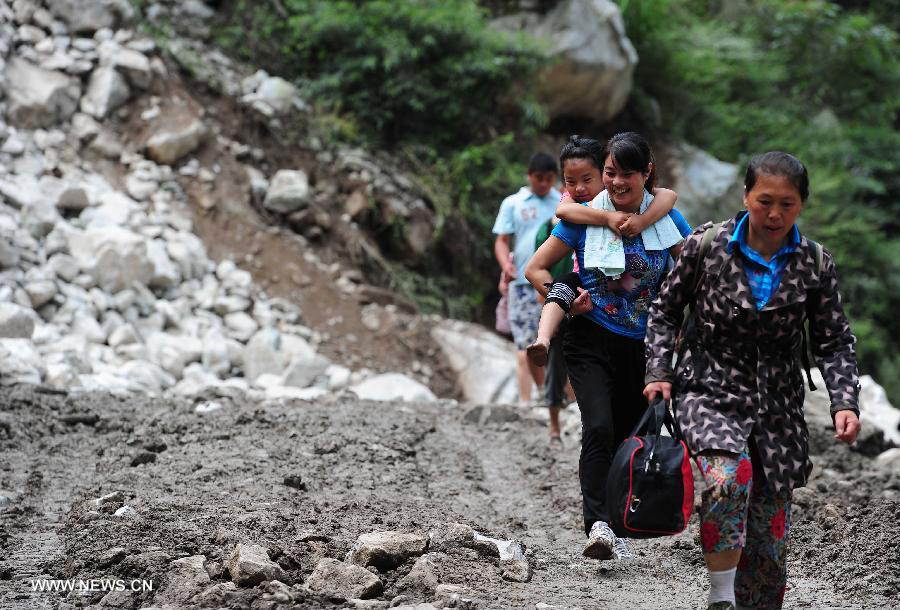 Villagers are evacuated on the restored road in Caopo Township of Wenchuan County, southwest China's Sichuan Province, July 20, 2013. The road lingking Caopo Township and outside which was badly damaged by previous mud-rock flow has been reopened on Saturday, which will facilitate future rescue work in the town.(Xinhua/He Haiyang) 